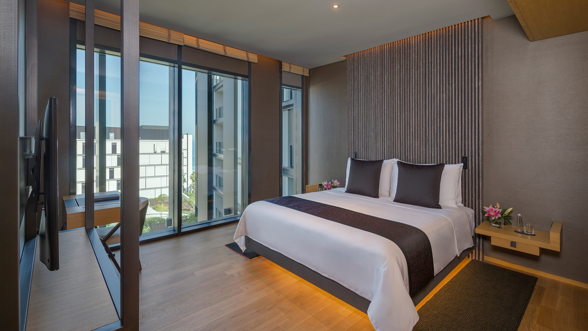 Elegant bed with plush pillows, modern decor at two-bedroom Banyan Tree Dubai residences; window view of buildings.